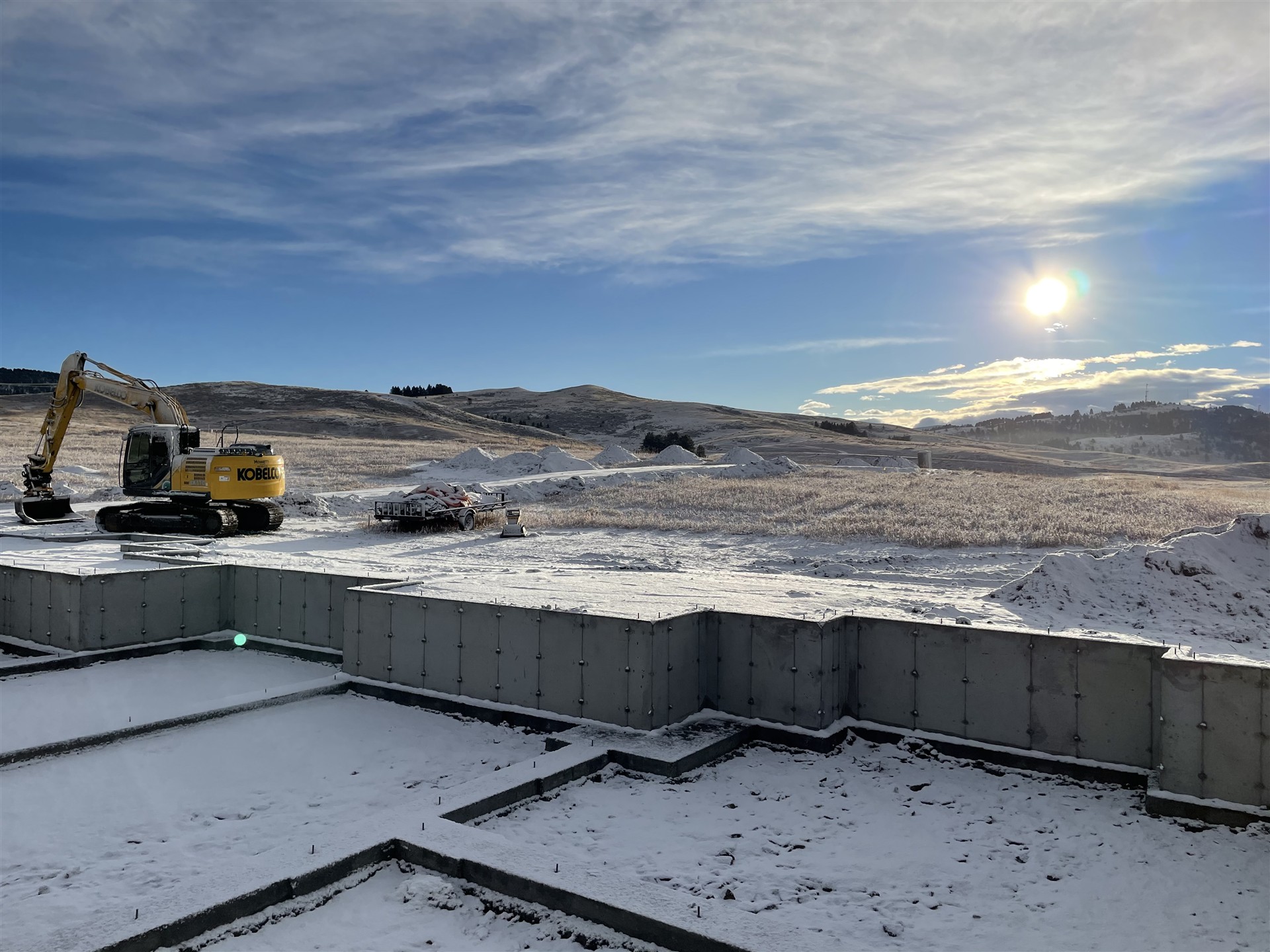 Excavator beside a snow-covered foundation site