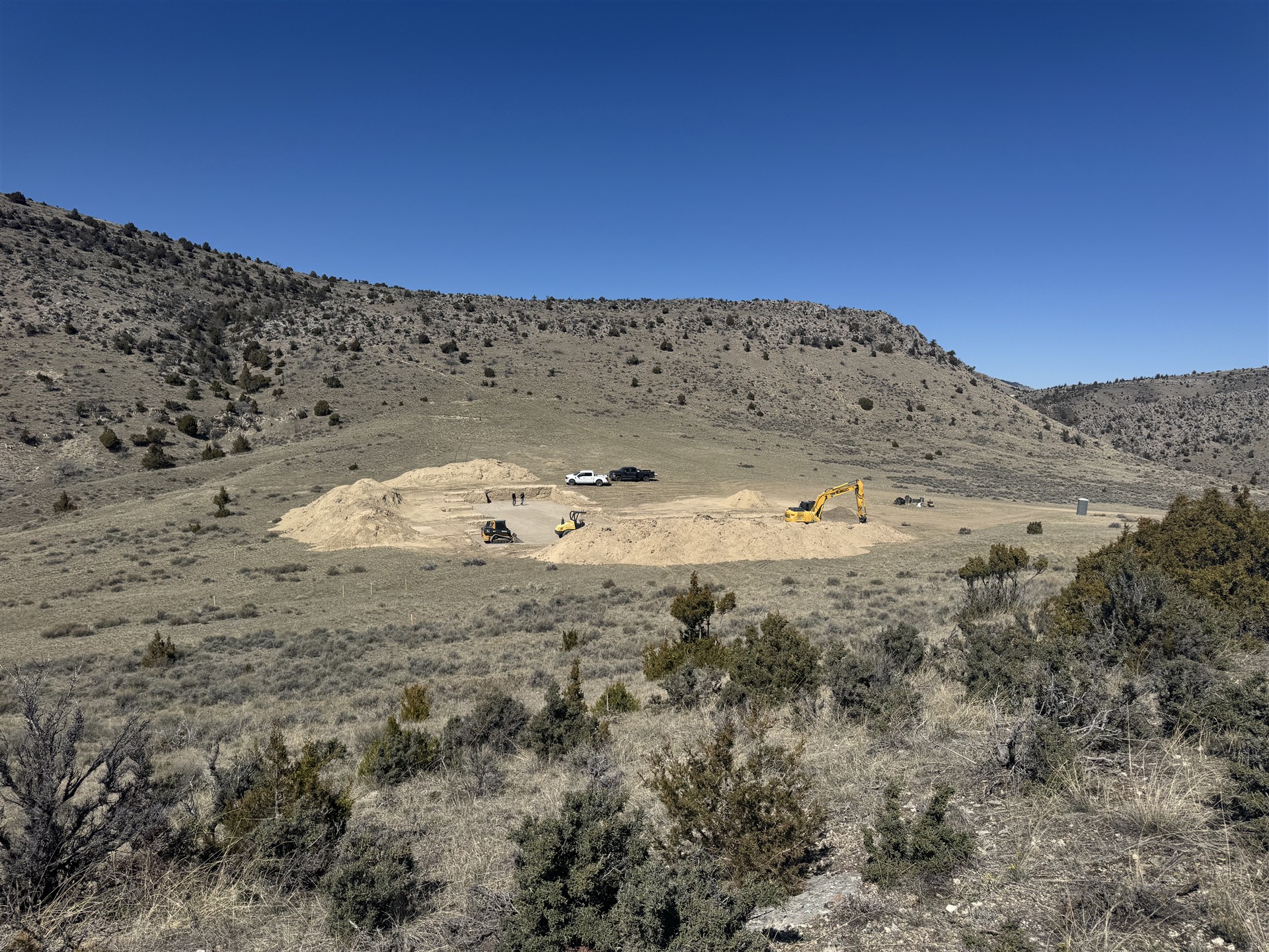 Excavation equipment preparing a building site among Montana hills