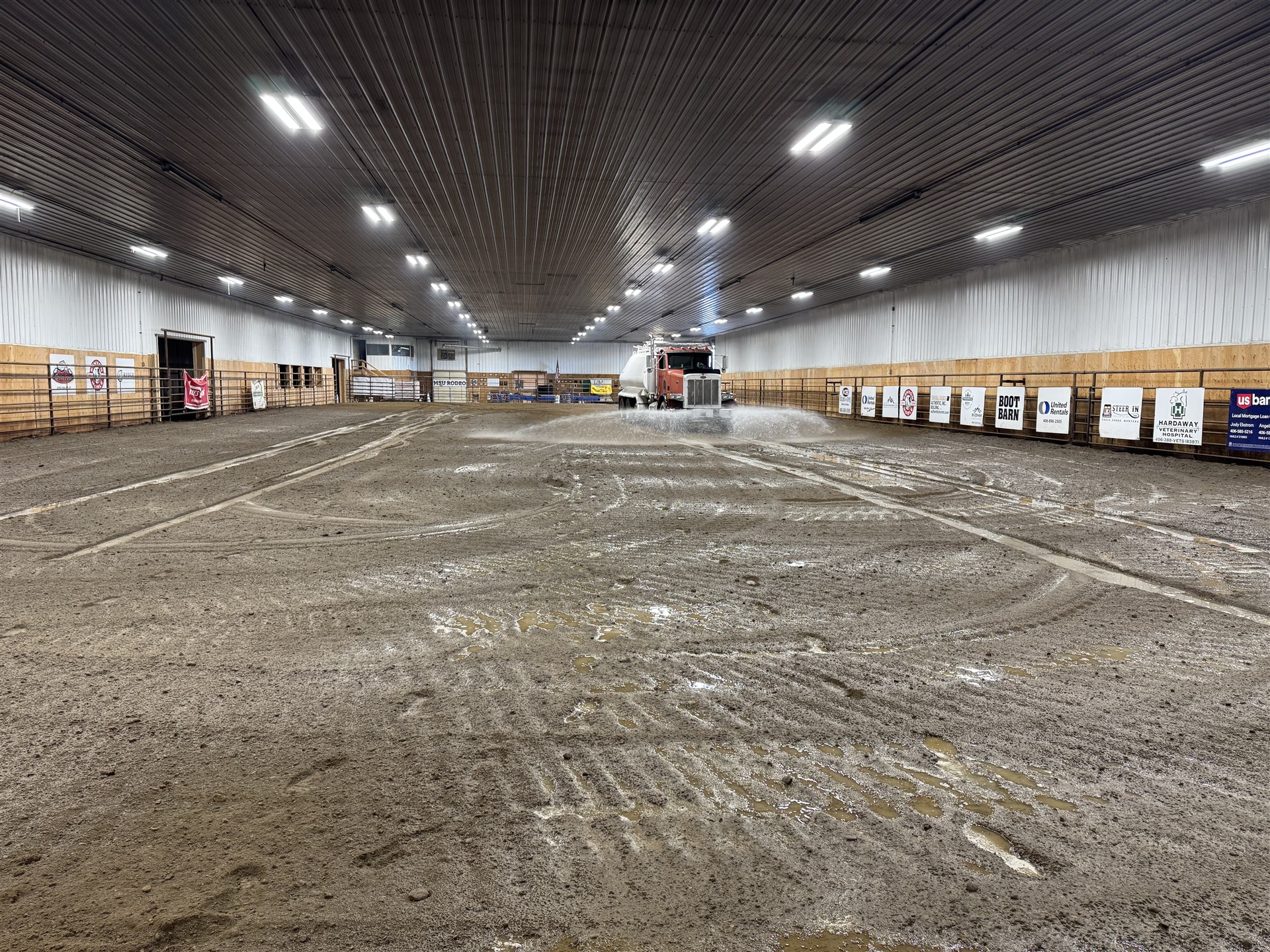 Water truck watering the dirt floor of an indoor arena